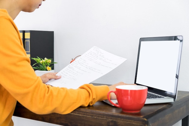 Close-up of a student filling out a FAFSA form at a desk, with a laptop displaying the FAFSA website in the background, bright lighting, focus on the form and the student's hands.