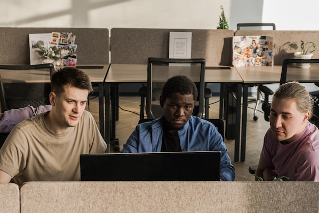 A diverse group of high school students working collaboratively on a coding project. They are using laptops and whiteboards, with visible teamwork and enthusiasm.