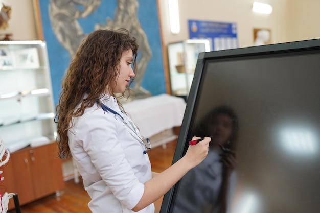 A classroom where a teacher is using a smartboard to deliver a lesson to students with learning disabilities. Some students are using tablets, while others are working with physical manipulatives. The teacher is providing individualized attention to each student, adapting the lesson to meet their specific needs.