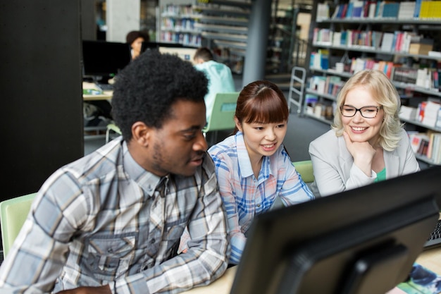 A teacher sitting at a desk, surrounded by high school students in a library with open books and computers. The students are engaged and collaborative, with the teacher providing guidance and support.