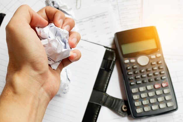A close-up of a hand holding a calculator over tax documents, symbolizing the complexity of property taxes.