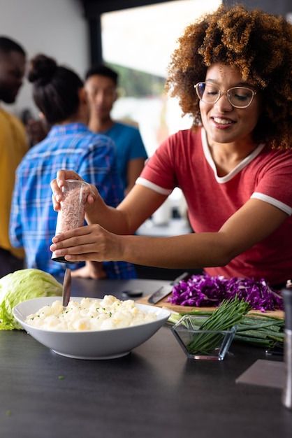 A close-up shot of a diverse group of employees happily preparing a healthy salad together in a bright office kitchen.