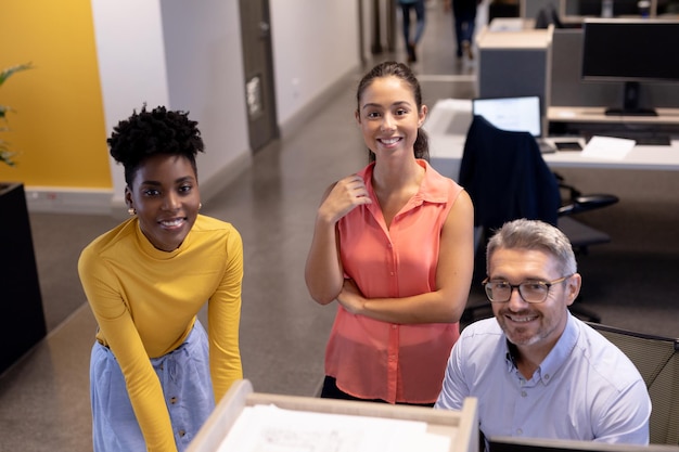 A diverse group of employees smiling and collaborating in a modern office setting, symbolizing a positive and supportive company culture that values employee benefits like student loan repayment assistance.