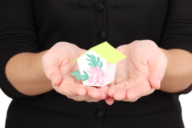 Close-up of a hand carefully holding a miniature house, symbolizing property insurance and asset protection. The background is blurred, focusing attention on the protective gesture.