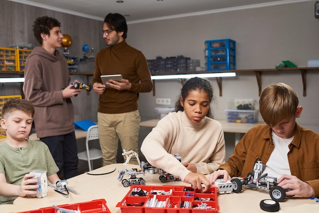 A group of middle school students working on a robotics project. They are gathered around a table, collaboratively assembling and programming a robot. The students look excited and engaged in the task, highlighting the hands-on nature of many STEM programs.