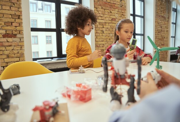 A classroom scene showing students working collaboratively on a STEM project. They are using various tools and materials, and the atmosphere is one of excitement and engagement. The teacher is facilitating the activity but not directly instructing.
