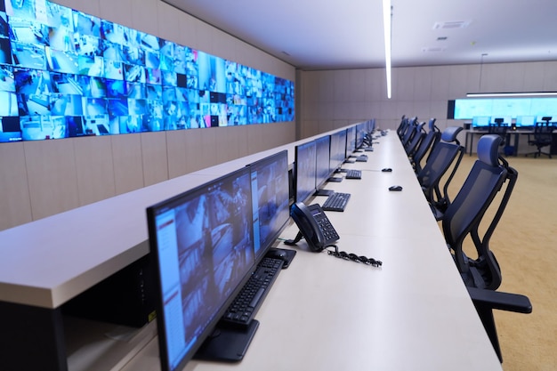 An image showing a school's security control room with multiple monitors displaying live feeds from security cameras. The room should be well-lit, showing security personnel actively monitoring the screens and communicating via radio.