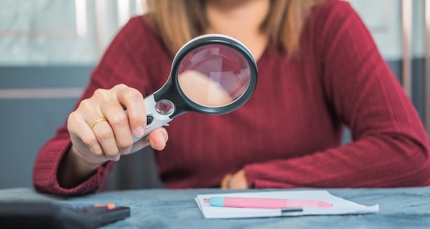 A close-up of a person reviewing a credit report with a magnifying glass, highlighting the importance of detail-oriented error checking.