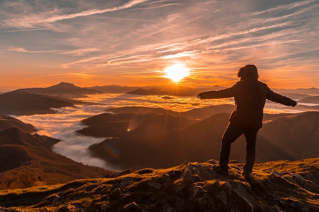 A person standing on top of a mountain peak at sunset, arms raised in triumph, symbolizing the personal fulfillment and sense of achievement gained through successful side hustles. The lighting is warm and golden, creating a sense of victory, freedom and aspiration.