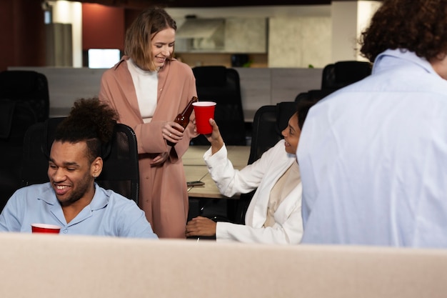 A group of employees are gathered around a table in a break room, reading a wellness program newsletter. They are engaged and discussing the content, showing positive communication and awareness of the program.