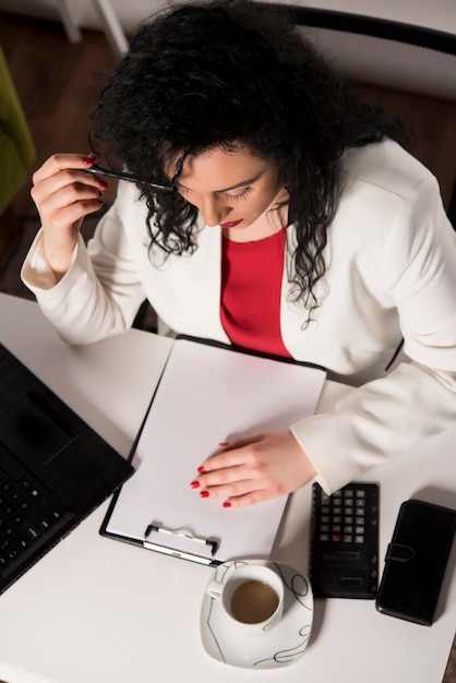 A person sitting at a desk reviewing financial documents with a calculator, representing budgeting and financial planning.