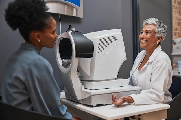 A smiling employee receiving a routine eye exam at a modern optometry clinic. The optometrist is using specialized equipment to check the employee's vision.