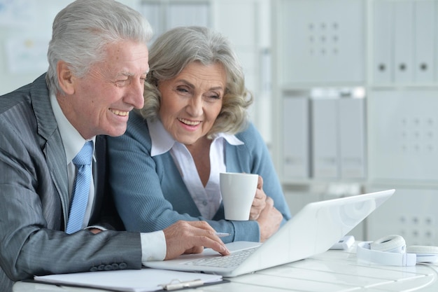 A mature couple discussing financial documents with a financial advisor in a bright, modern office setting, emphasizing the importance of professional guidance and planning for various financial scenarios.