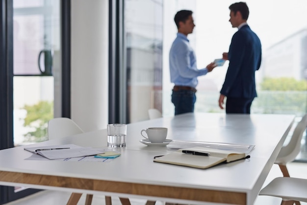 Two professionals shaking hands across a table in a modern office setting, symbolizing a successful negotiation of employee benefits.